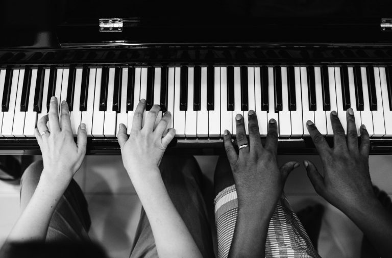 black and white photo of two hands playing the piano