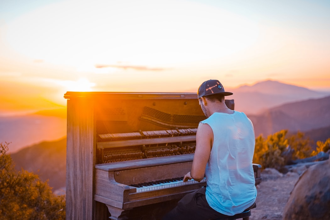 man playing piano outdoor during sunset